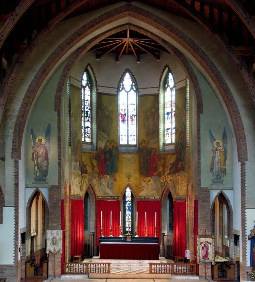 James Clark's apse painting: ranks of angels in red and gold gathered around the Holy Trinity above the high altar.