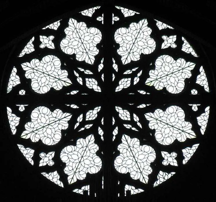 The west rose window in silhouette, its flowing stone tracery dark against the light.