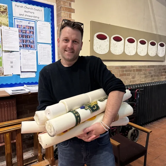 A man holds a bundle of large paschal candles for recycling
