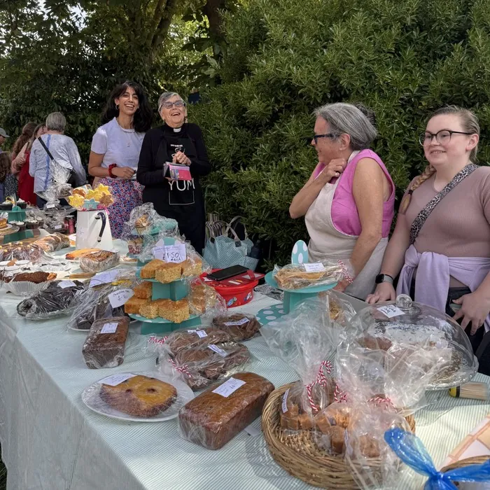 Volunteers smiling behind a table laden with home-baked cakes