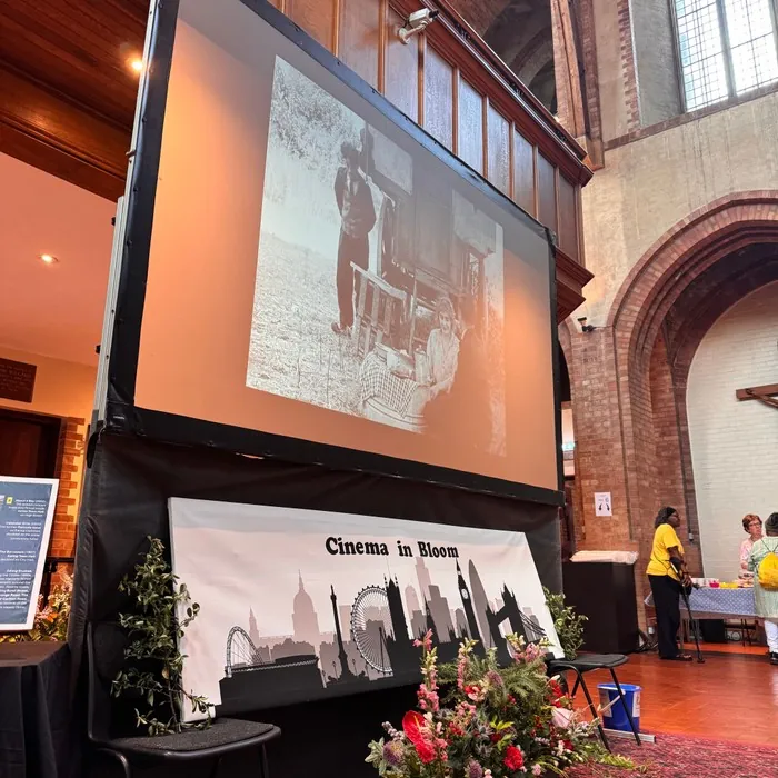A cinema screen showing an old black-and-white photograph above a Cinema in Bloom banner in the church hall